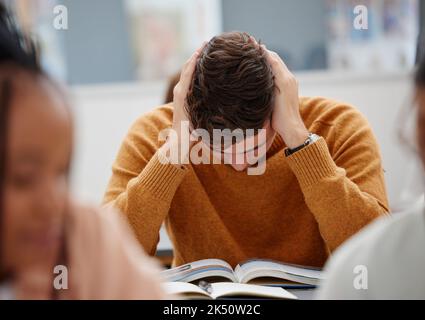 University, study and tired student reading book in class while studying for test or exam. Education, stress and burnout man with headache, knowledge Stock Photo