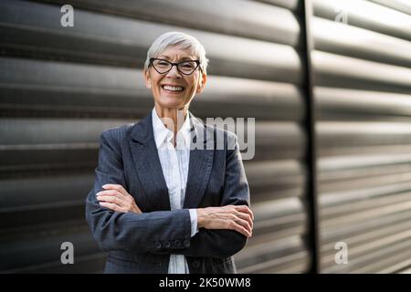 Outdoor portrait of successful senior businesswoman in front of company building. Stock Photo