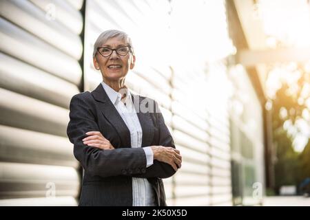 Outdoor portrait of successful senior businesswoman in front of company building. Stock Photo
