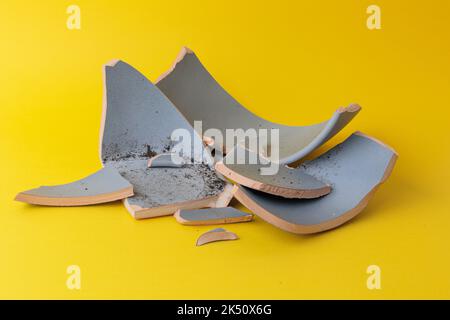 A closeup shot of a broken flower pot on a yellow background Stock Photo