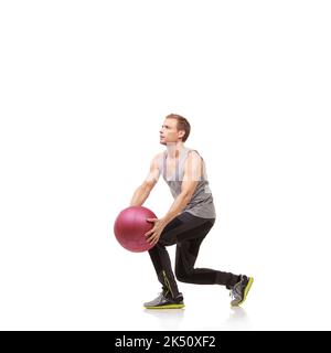 Toning his abs. A young man working out with a medicine ball on a white background. Stock Photo