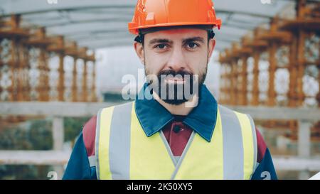 Portrait of confident construction workman wearing safety uniform standing in building area and looking at camera. People and occupation concept. Stock Photo
