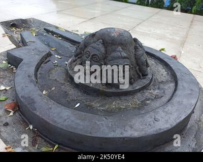 A Shiva linga made with a black stone on plane surface with surrounding made of tiles Stock Photo