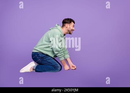 Full size photo of handsome young man flying invisible broom witchcraft dressed stylish khaki clothes isolated on purple color background Stock Photo