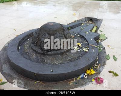 A Shiva linga made with a black stone on plane surface with surrounding made of tiles Stock Photo