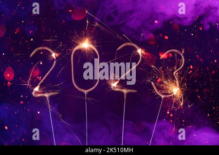 2023 Happy new year Silvester greeting card banner with burning golden sparklers shiny glitter bokeh and colorful smoke Stock Photo