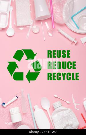 Plastics on pink pastel background with recycling symbol and reuse reduce recycle text Stock Photo