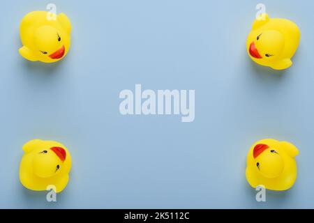 Four small yellow rubber ducks frame with copy-space in center on blue background top view Stock Photo