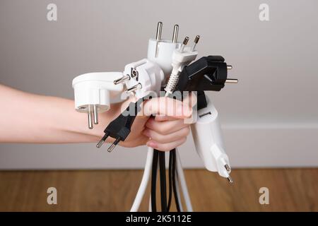 Hand holding bunch of electric plugs. Electric power consumption or rising electricity price concept Stock Photo