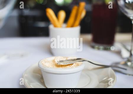 Butter spreader knife on white dip and breadsticks on background. Delicious appetizer plate on fancy restaurant Stock Photo