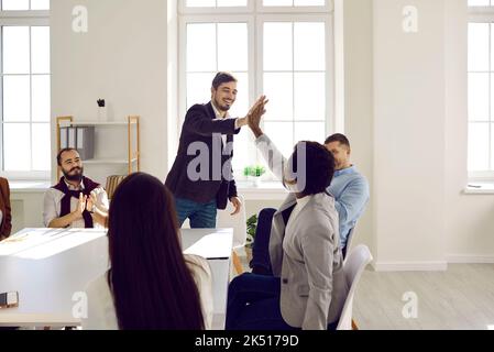 Colleagues giving high five greeting each other or express respect during business meeting in office Stock Photo