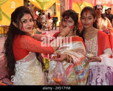 Happy Bengali Ladies in tradition attire offering sweets to each other during Vijaya Dashami celebration in India Stock Photo