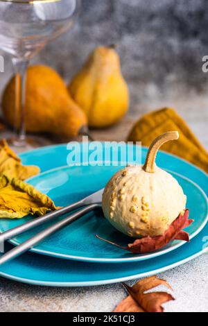 Autumnal place setting with blue ceramic dinnerware and seasonal decoration on concrete table Stock Photo