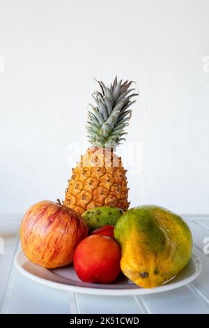 Delicious halved papaya served on plate near assorted colorful fruits and glass of fresh orange juice placed in white table Stock Photo