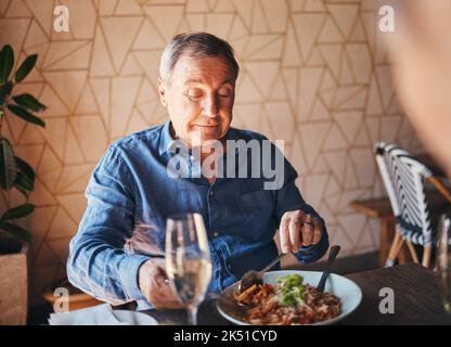 Senior man eating healthy and nutrition food at restaurant happy, satisfied and at table. Alone, elderly male and customer enjoy a delicious, meal Stock Photo