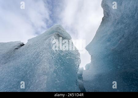 Rough ice formations of Vatnajokull Glacier located against blue sky with white clouds on winter day in Iceland Stock Photo
