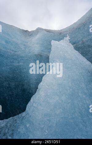 Rough ice formations of Vatnajokull Glacier located against blue sky with white clouds on winter day in Iceland Stock Photo