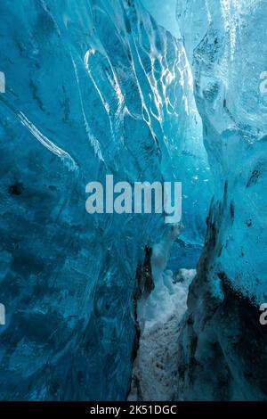 Narrow snowy path between blue ice walls in cave of Vatnajokull Glacier on winter day in Iceland Stock Photo