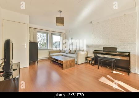 Interior of spacious living room furnished with comfortable couch and coffee table on parquet floor near big black piano against white brick walls Stock Photo