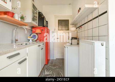 Counter with white cupboards and modern kitchenware with various special utensils placed in light stylish kitchen Stock Photo