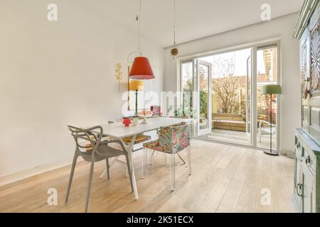 Light room with wooden parquet floors and glass doorways furnished with wooden dining set and aged cupboard in daylight Stock Photo