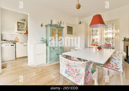 Light room with wooden parquet floors and glass doorways furnished with wooden dining set and aged cupboard in daylight Stock Photo