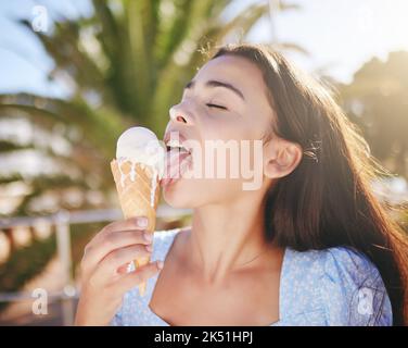 Ice cream cone eating, woman and summer dessert to enjoy on vacation, holiday and relaxing weekend in Portugal. Happy young girl licking melting Stock Photo