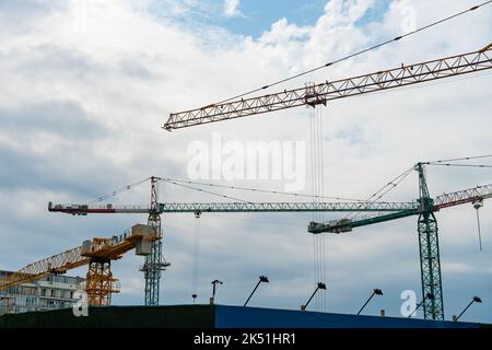 Close-up of a lot of construction cranes against a cloudy sky. Concept of construction, industry, business Stock Photo