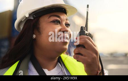 Logistics, delivery and black woman in communication via radio for manufacturing supply chain about shipping. Smile, engineer and happy manager in Stock Photo