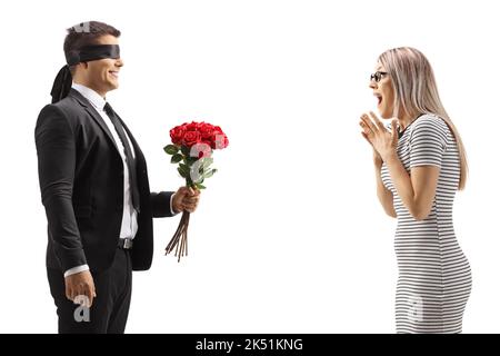 Man with blindfold giving a bunch of red roses to an excited young woman isolated on white background Stock Photo