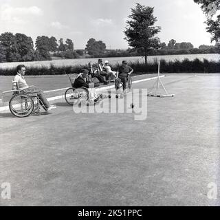 1964, historical, in the grounds of Stoke Mandeville Hospital, home of the National Spinal Injuries Centre - established in 1944 by Dr. Ludwig Guttmann - wheelchair competitors taking part in a bowls tournament. Stoke Mandeville in Aylesbury, Buckinghamshire, England, UK, was the birthplace of the Paralympic movement in 1948, the year of the post-war London Olympics, when the first competition for wheelchair athletes took place. 16 injured serviceman and women took part in what was known as the Stoke Mandeville Games, which later became the Paralympic Games. Stock Photo