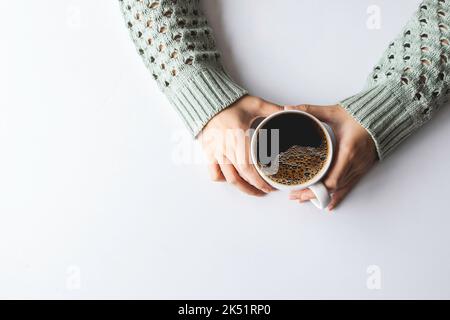 Woman's hands holding cup with coffee on white table background, top view Stock Photo