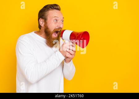 Photo portrait of attractive young man yell hold loudspeaker empty space wear stylish white clothes isolated on yellow color background Stock Photo