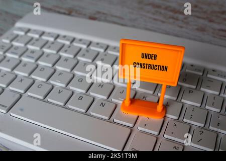 Under construction sign on top of computer keyboard. Computer system under construction, maintenance, repair concept. Stock Photo