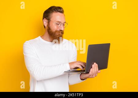 Portrait of positive intelligent person hold use wireless netbook networking isolated on yellow color background Stock Photo