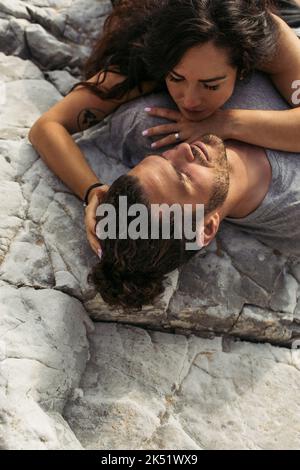 top view of bearded man with closed eyes and tattooed girlfriend lying on rocks,stock image Stock Photo