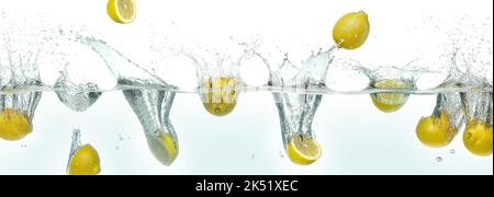 Many lemons splashing in water. Side panoramic view on white background. Stock Photo