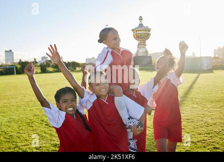 Sports. soccer and young girls with trophy celebrate, happy and excited outside on field for their victory. Team, players and female children are Stock Photo