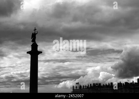 Sign of the cross. Concept. Angel with a cross on Alexander Column and sculptures on the roof of The Winter Palace against a storm sky. Black and whit Stock Photo