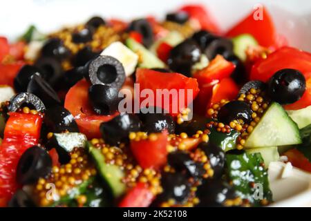 Defocus closeup summer salad. Classic Greek salad from tomatoes, cucumbers, red pepper, onion with olives, oregano and feta cheese. Fresh mixed vegeta Stock Photo