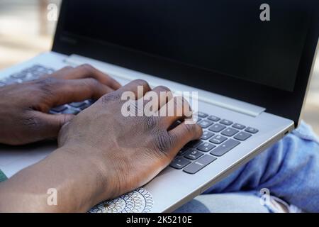 close up of black man working remotely with a laptop Stock Photo