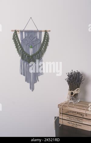 iris and green macramé wall hanging fiber art decoration with lotus flower symbol. Macrame handmade knotting technique. Cotton rope wood and glass Stock Photo