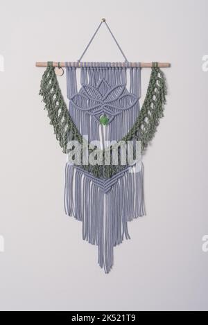 iris and green macramé wall hanging fiber art decoration with lotus flower symbol. Macrame handmade knotting technique. Cotton rope wood and glass Stock Photo