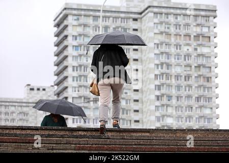Woman with umbrella walking up the steps on city buildings background. Rain in autumn city Stock Photo