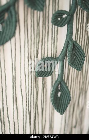 green leaf branch handmade macrame artistic wall hanging fiber art decoration leaf symbol wood stick white background interior plant macramé deco Stock Photo