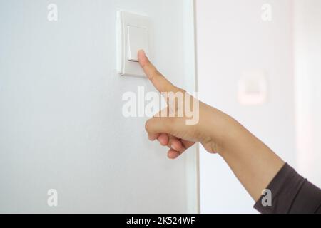A finger turning on lighting switch . Stock Photo