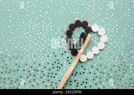 Above view of black activated charcoal and white fluoride toothpaste tablets with bamboo toothbrush. Dental care concept. Minimal mint green dotted. Stock Photo