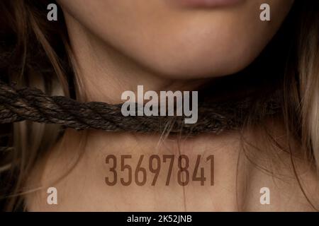 girl with a rope around her neck and a digital number on her chest, human trafficking, slavery, power over people, rope around a person's neck Stock Photo