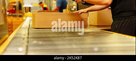 Worker scanning box on conveyor belt in warehouse Stock Photo
