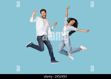 Glad excited young caucasian man and arabic woman have fun together, jumping in air Stock Photo